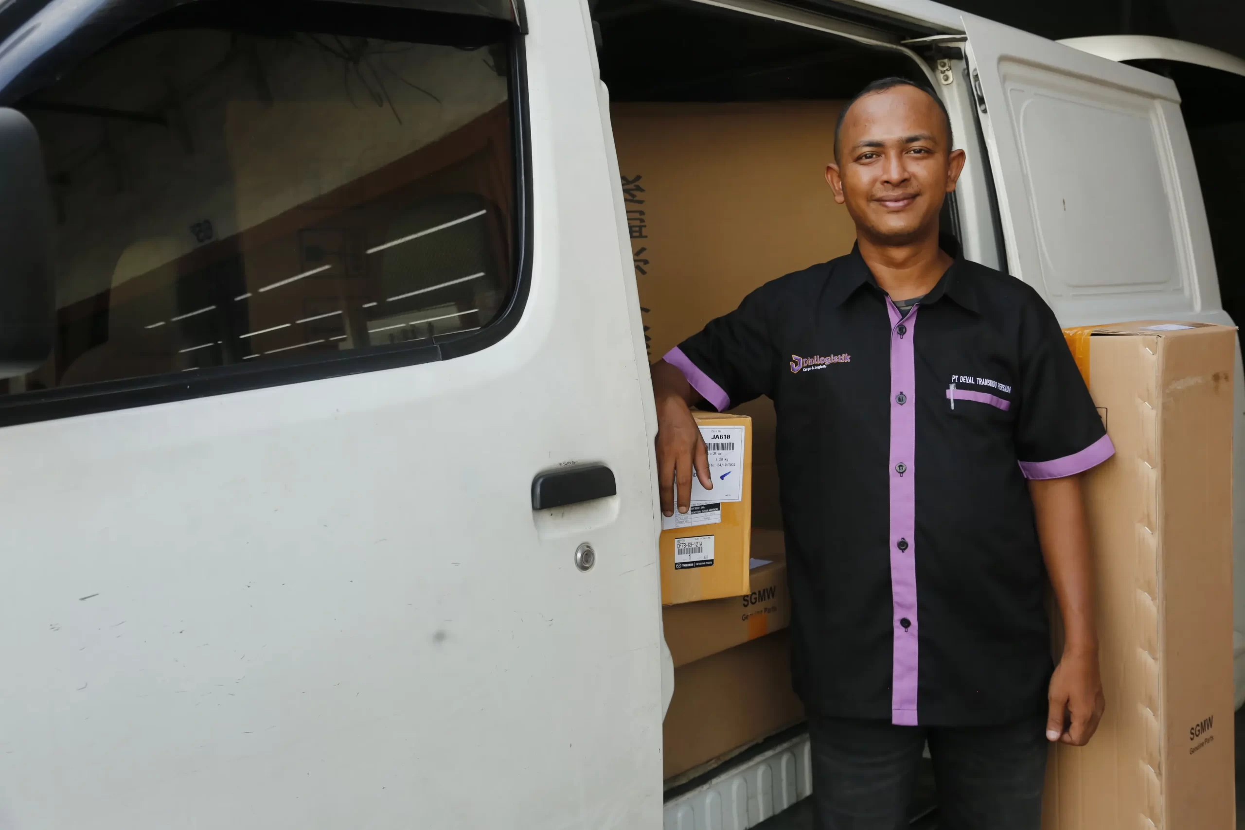 gambar anggota diallogistik dibelakang pickup dengan senyum membawakan paket yang banyak